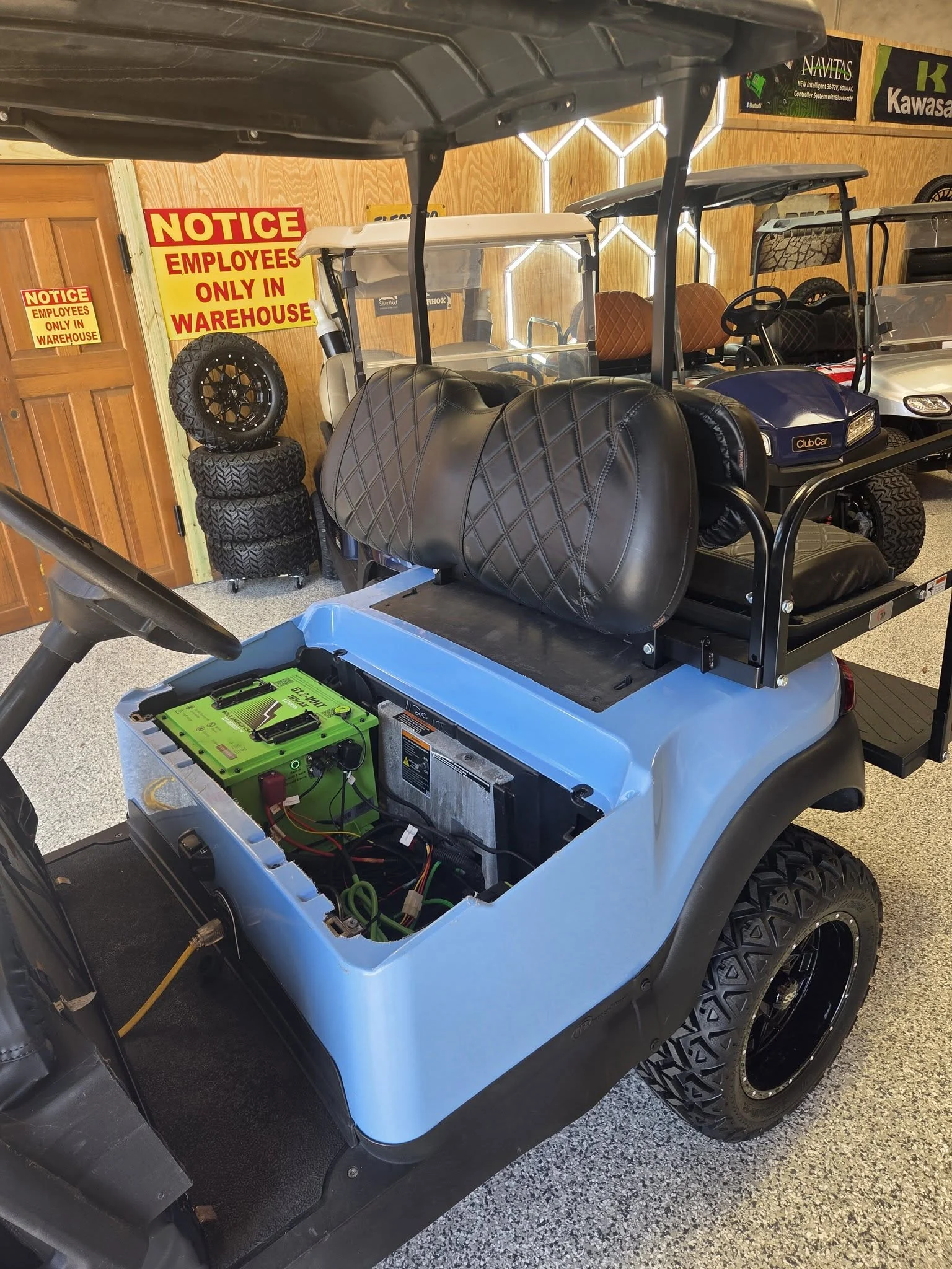 Blue golf cart with a green lithium battery installed under the raised seat in the Gayle Battery showroom